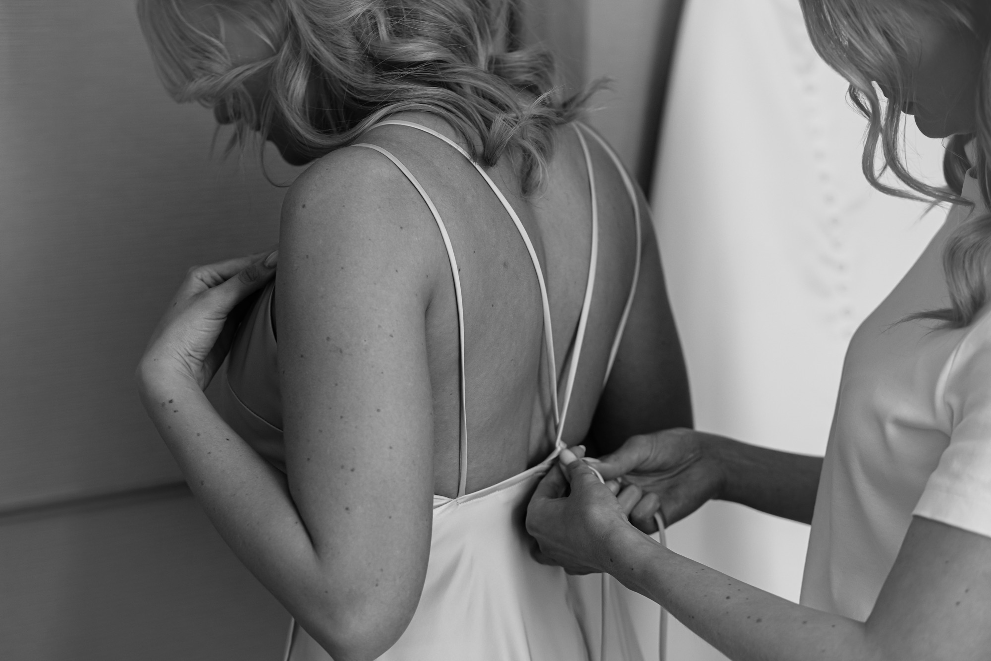 Svartvit: klänning knyts i ryggen på brudtärna