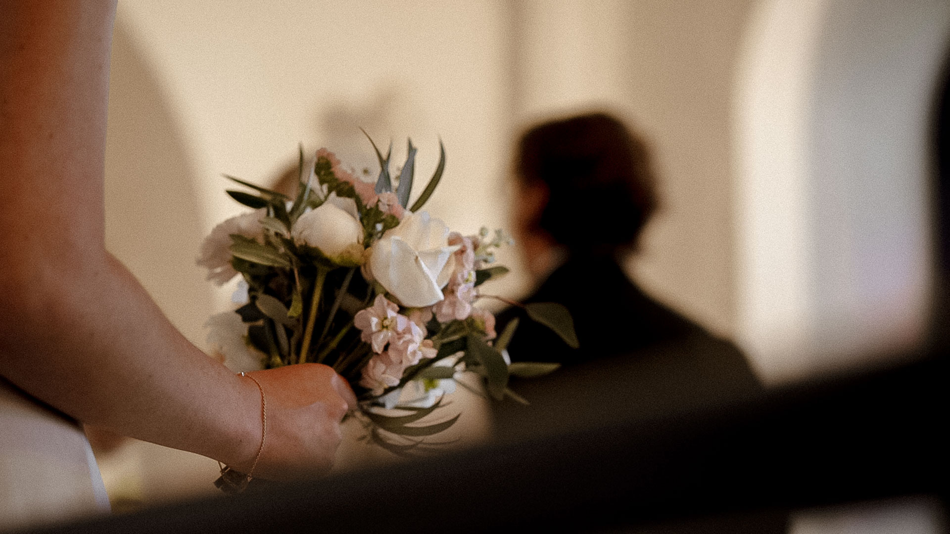 Bröllopsbukett i fokus, person suddig i bakgrunden